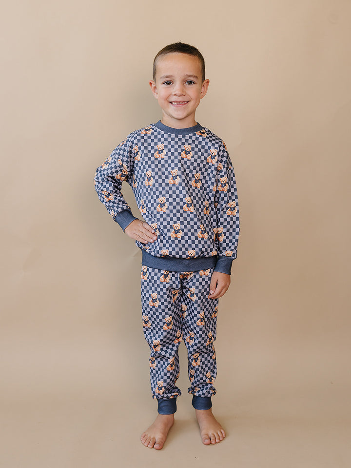 Child standing in the matching Checkered Bear Vibes long-sleeve top and jogger pants.