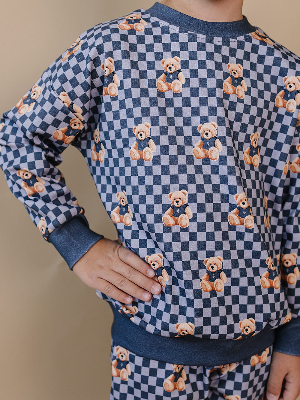 Close-up of a child wearing the Checkered Bear Vibes crewneck top and matching joggers.