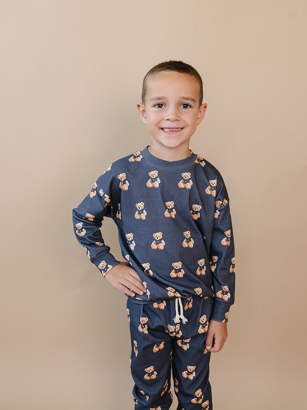 Smiling child modeling the dark charcoal Bear Vibes cotton jogger set.