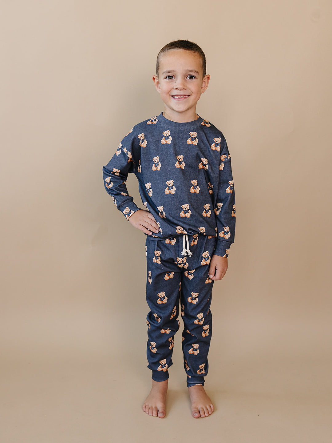 Full-length front view of a child wearing the dark charcoal teddy bear-print jogger set.