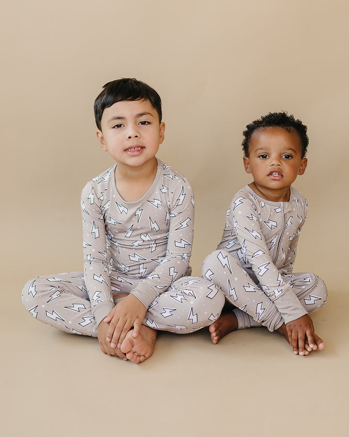 Two boys posing together in Latte Bolts bamboo two-piece sets against a warm neutral background.