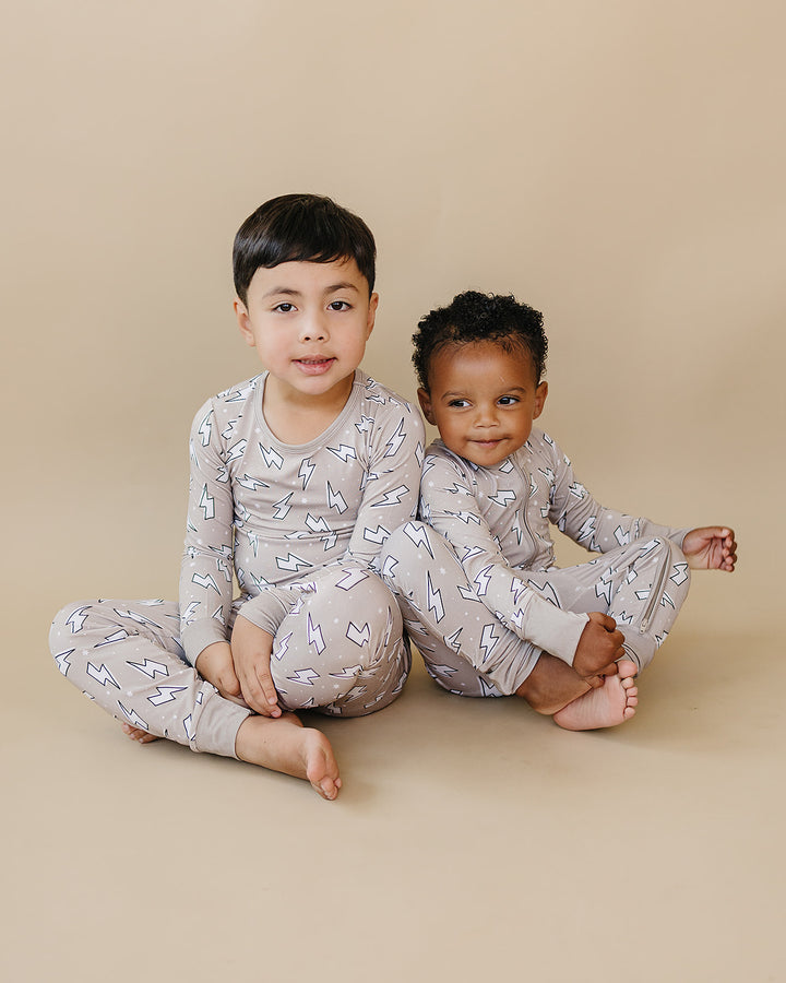 Two children sitting side by side in matching Latte Bolts bamboo sets, showing the coordinated sibling look.
