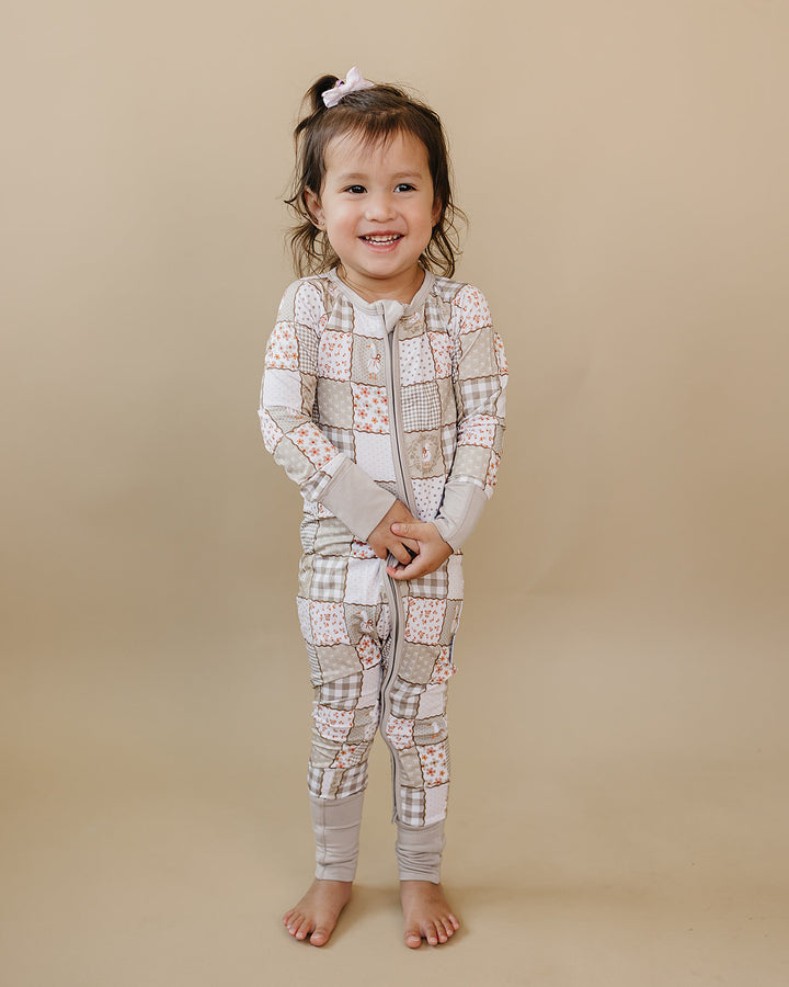 Toddler modeling the Cottage Goose bamboo zip romper in a full-length front view against a beige studio backdrop.