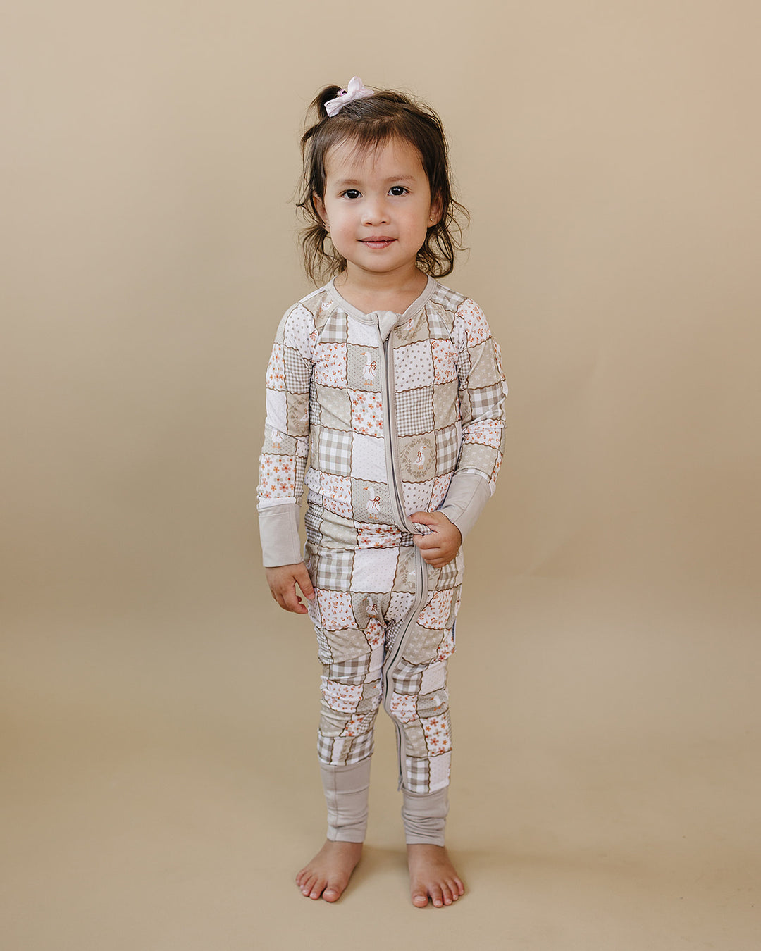 Smiling toddler modeling the Cottage Goose bamboo zip romper in a full-length front view.
