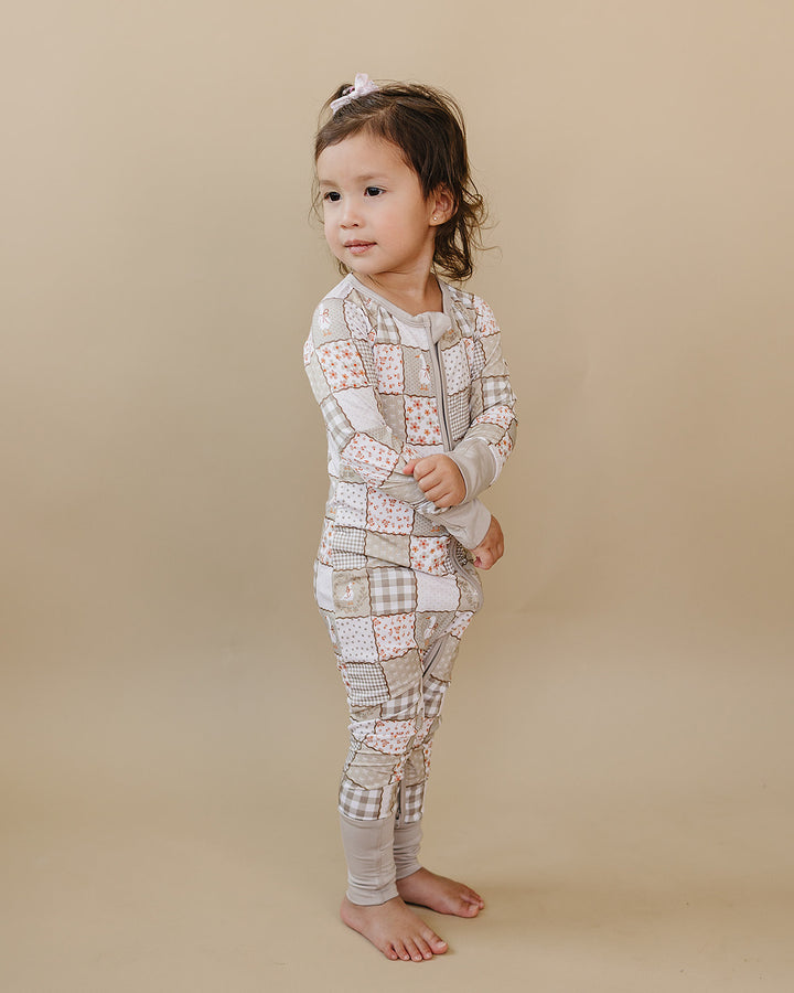 Side view of a toddler wearing the Cottage Goose bamboo zip romper against a warm neutral background.