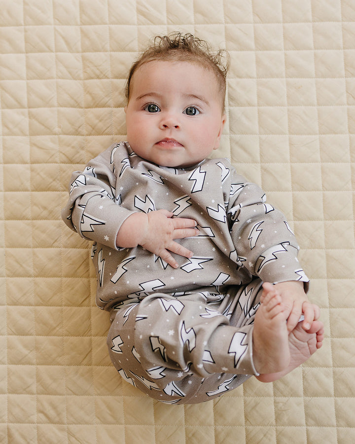 Baby sitting on a beige quilt in the Latte Bolts cotton jogger set, showing the matching top and pants.