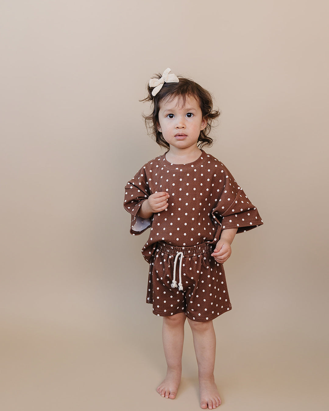 Toddler girl wearing Lucky Panda Kids Brown Polka Shorts Set — brown and white polka dot cotton two-piece outfit