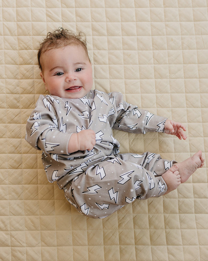 Close-up of a baby posing on a quilt in the Latte Bolts jogger set with the lightning bolt print clearly visible.