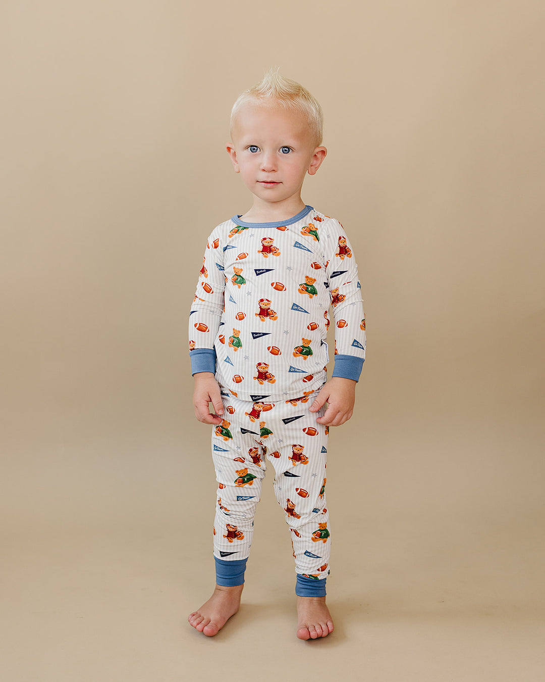 Toddler wearing the Touchdown Teddy bamboo two-piece set against a neutral beige background.