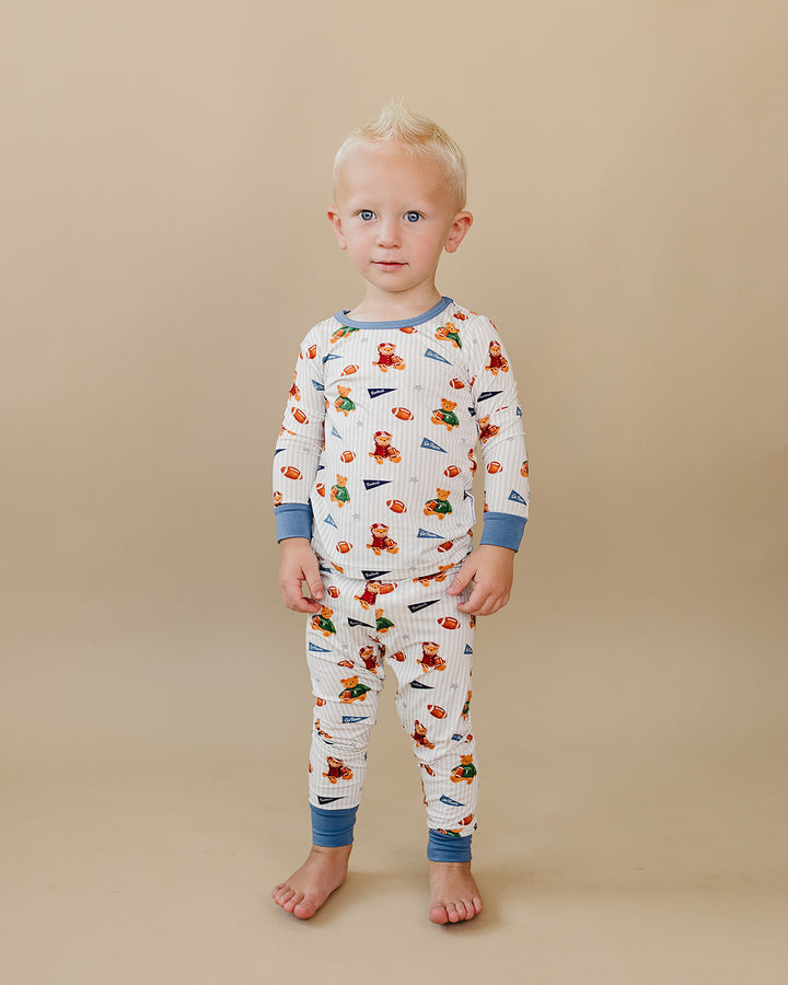 Toddler wearing the Touchdown Teddy bamboo two-piece set against a neutral beige background.