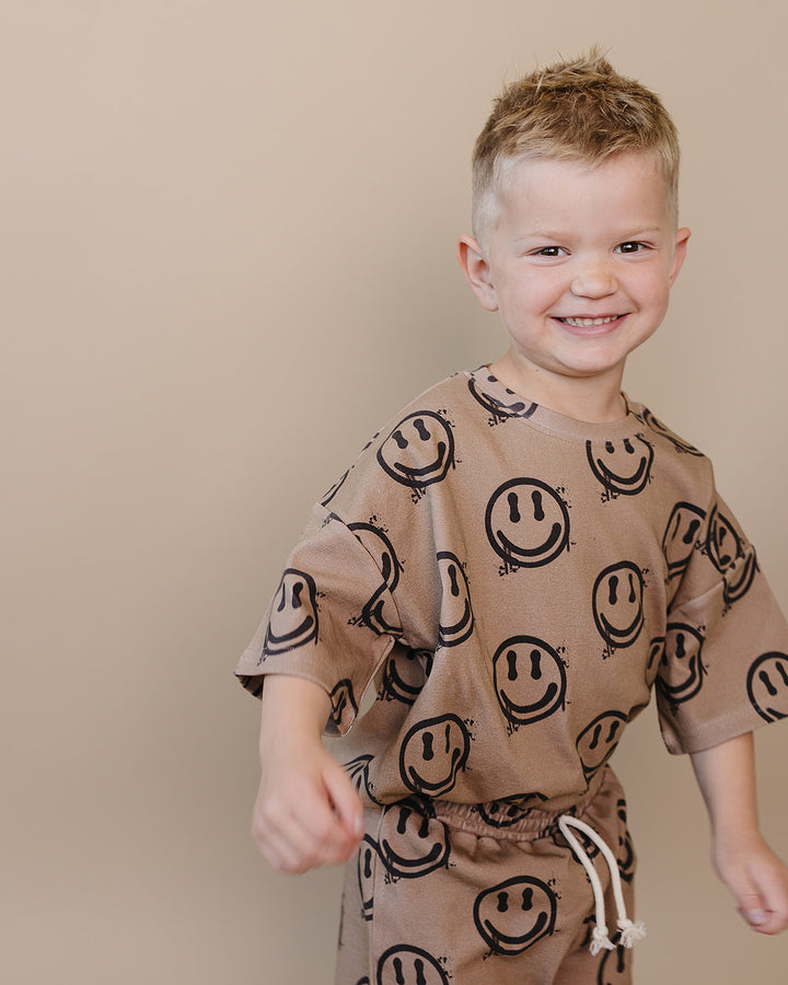 Toddler boy wearing Lucky Panda Kids Smiley Brown Shorts Set — warm brown all-over smiley face print cotton two-piece outfit