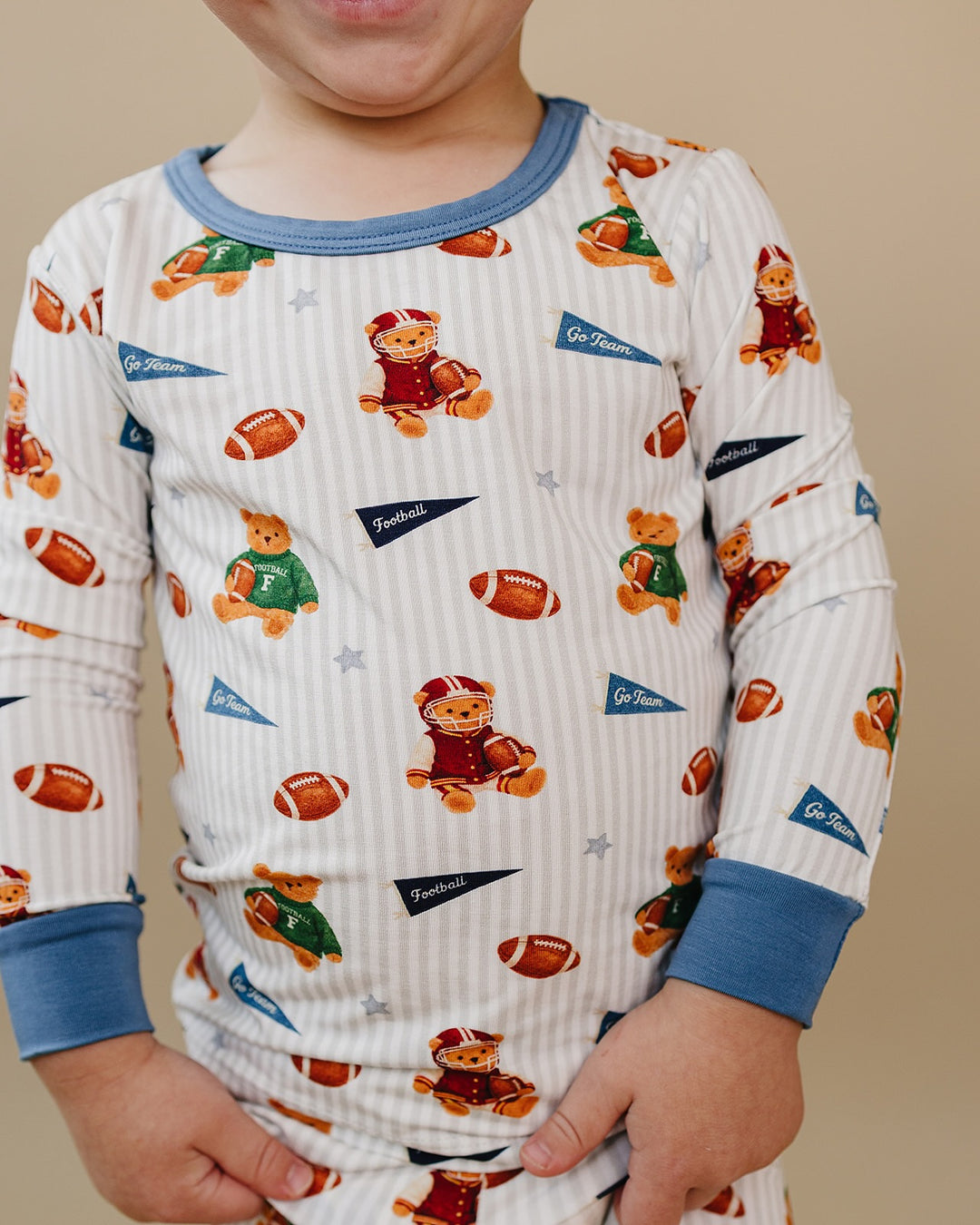 Close-up of a child wearing the Touchdown Teddy bamboo two-piece set with football and teddy bear print.