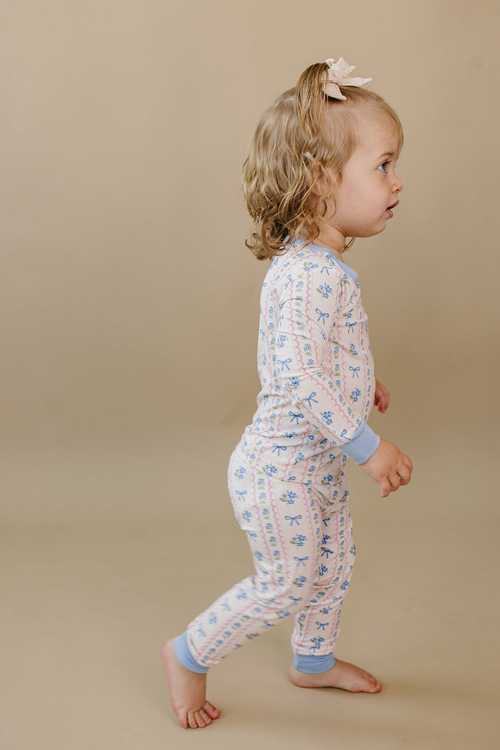 Side view of a toddler walking in the Whimsy Bloom floral bamboo two-piece set.