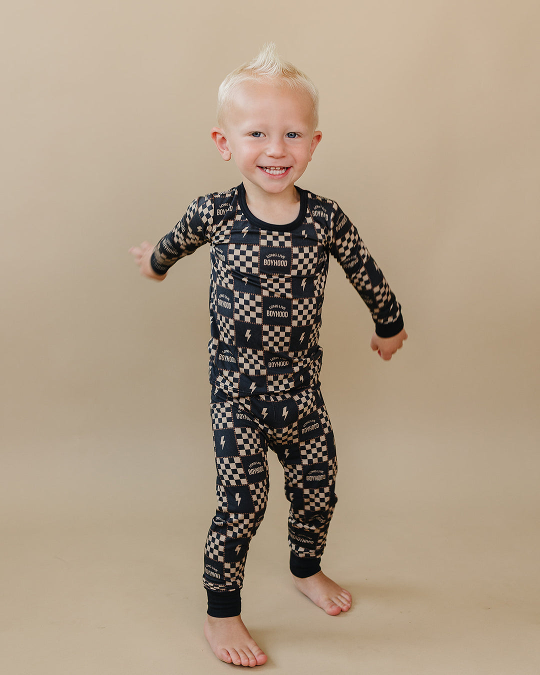 Toddler stepping forward in the Long Live Boyhood charcoal and beige bamboo two-piece set.