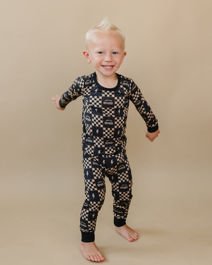 Toddler stepping forward in the Long Live Boyhood charcoal and beige bamboo two-piece set.