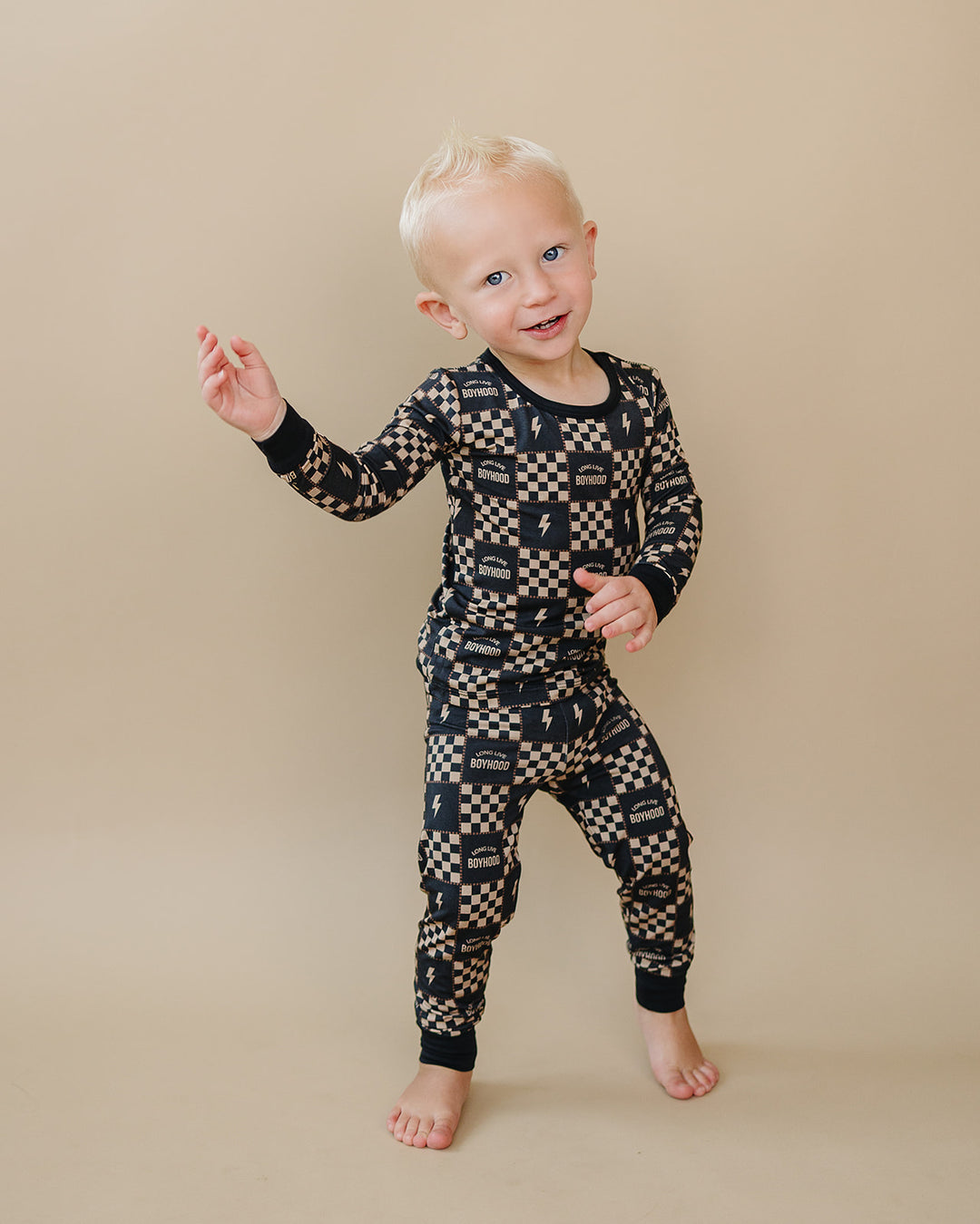 Toddler raising one arm while wearing the Long Live Boyhood lightning bolt-print bamboo two-piece set.