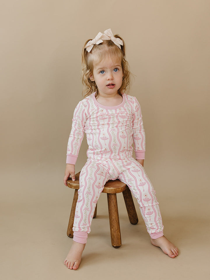 Toddler sitting on a wooden stool in the Little Ballerina bamboo pajama set.