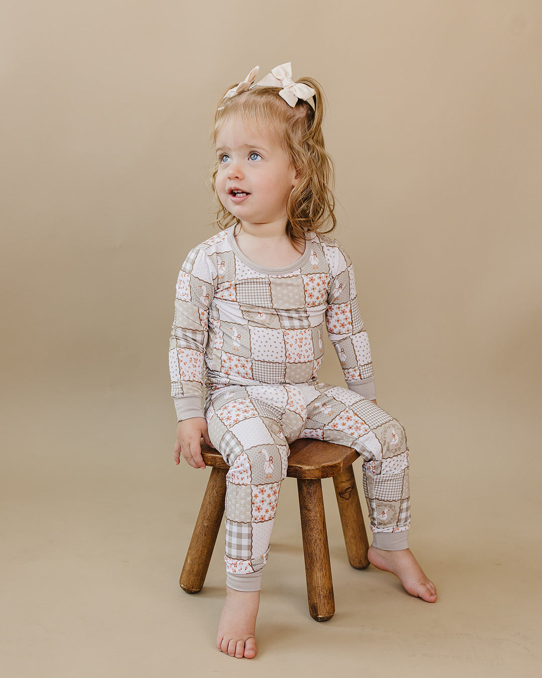Toddler sitting on a wooden stool in the Cottage Goose bamboo two-piece set.