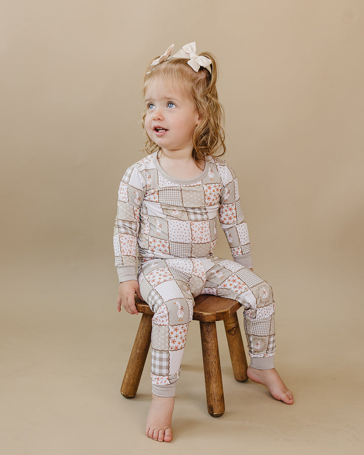 Toddler sitting on a wooden stool in the Cottage Goose bamboo two-piece set.