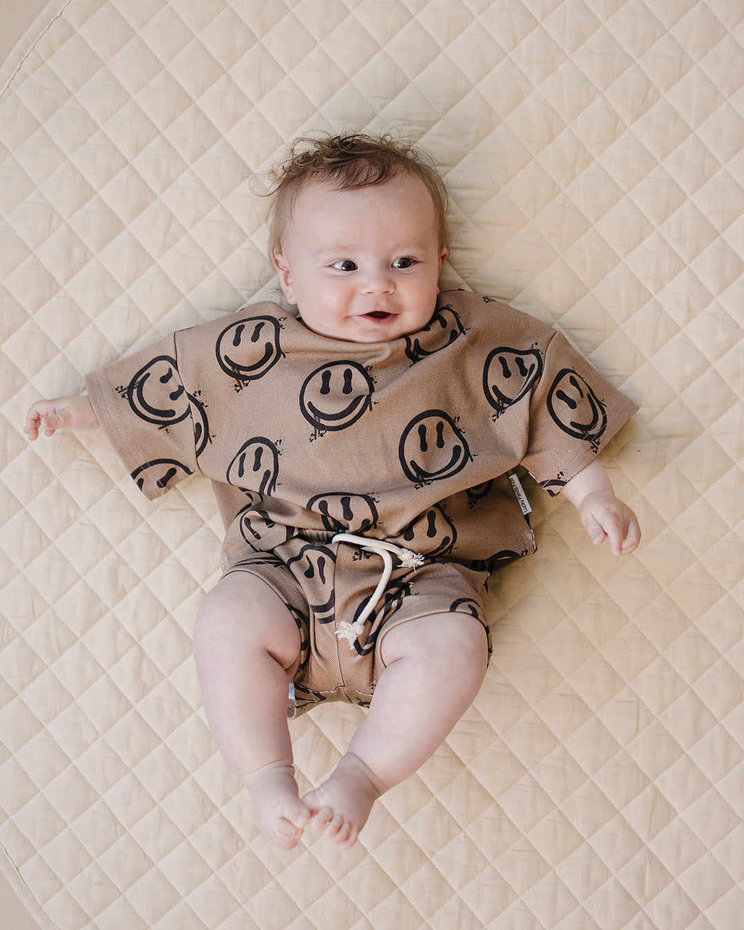 baby boy wearing Lucky Panda Kids Smiley Brown Shorts Set — warm brown all-over smiley face print cotton two-piece outfit