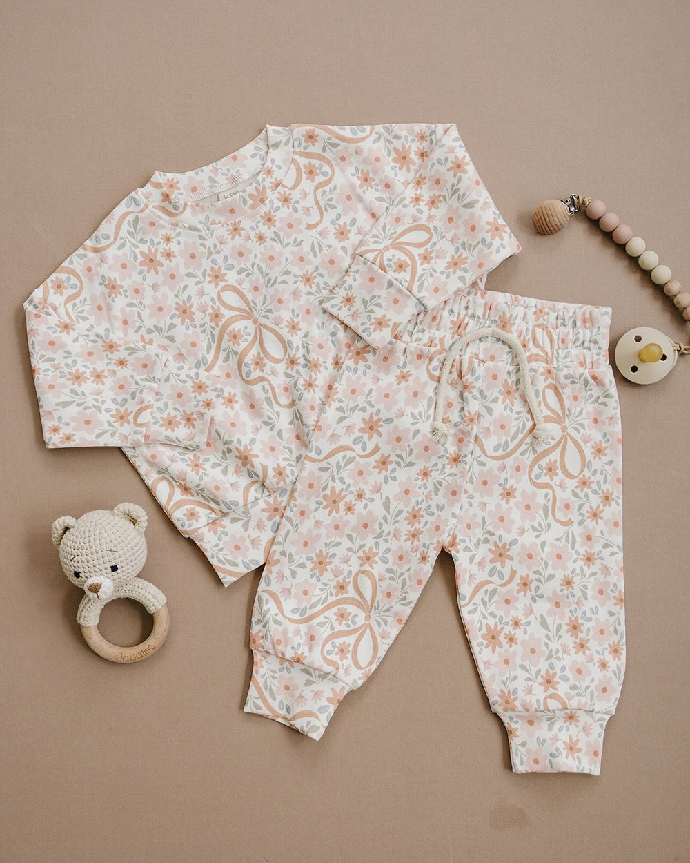 Baby wearing the Lucky Panda Kids Cozy Daisy cotton jogger set while lying on a cream quilt.
