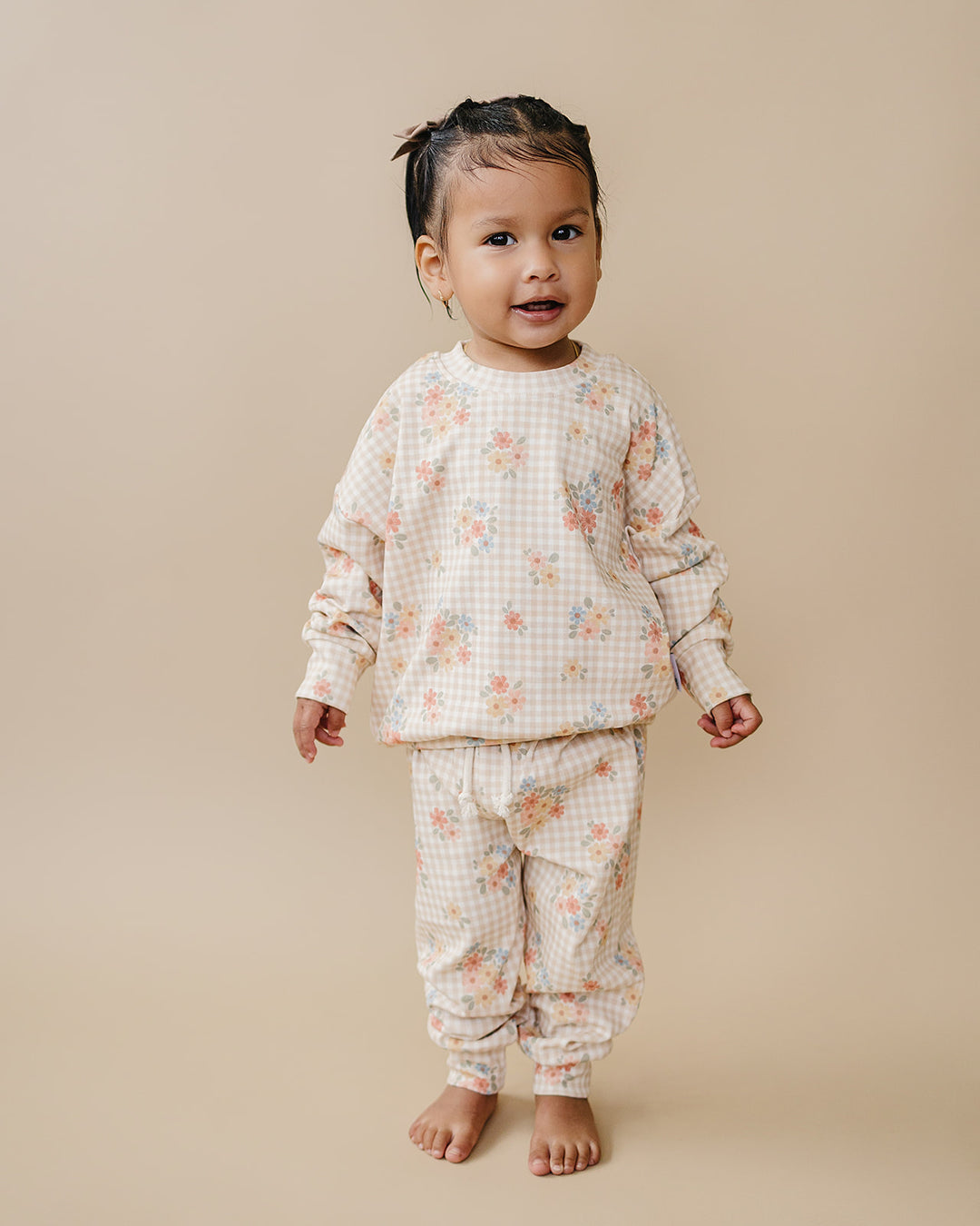 Child wearing Beige Gingham playing beside a baby in the Wild Flower cotton jogger set.