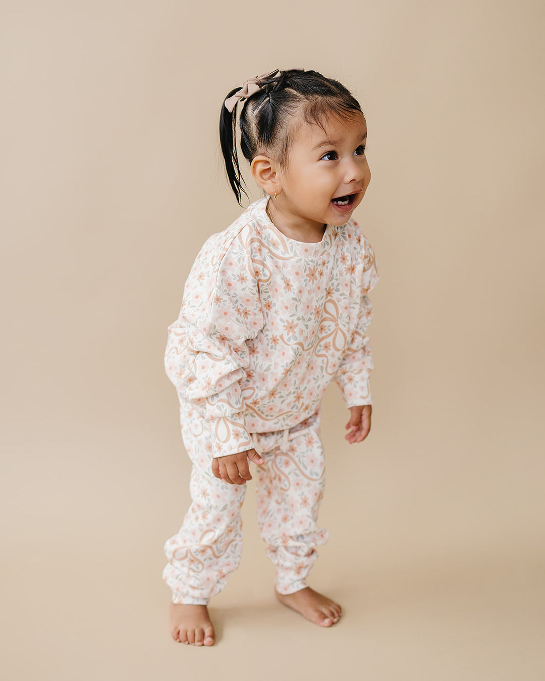 Toddler modeling the Cozy Daisy cotton jogger set against a warm neutral background.