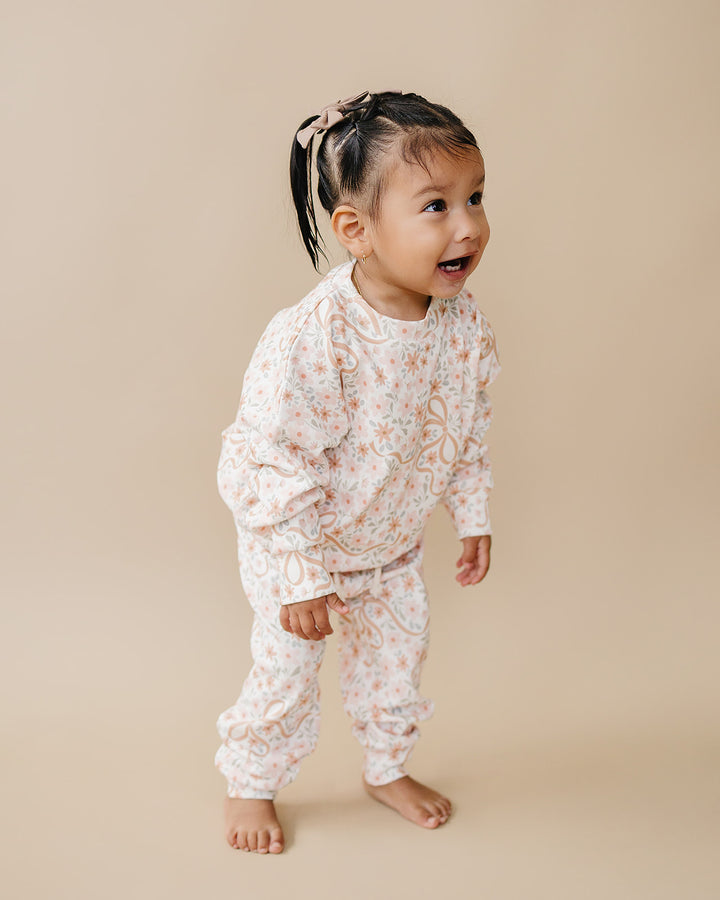 Toddler modeling the Cozy Daisy cotton jogger set against a warm neutral background.