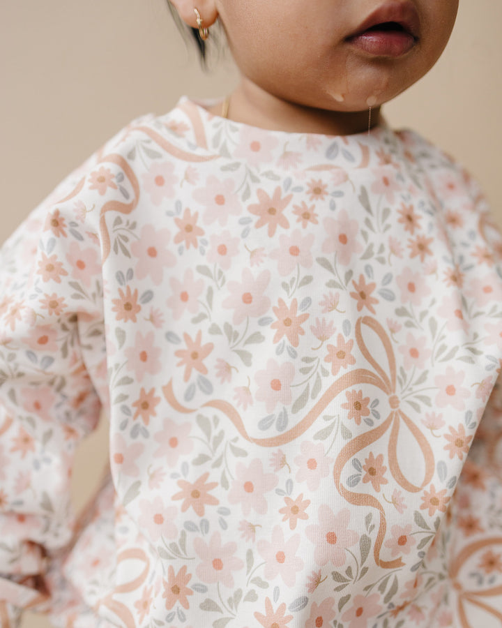 Smiling toddler wearing the Lucky Panda Kids Cozy Daisy cotton sweatshirt and matching jogger pants.
