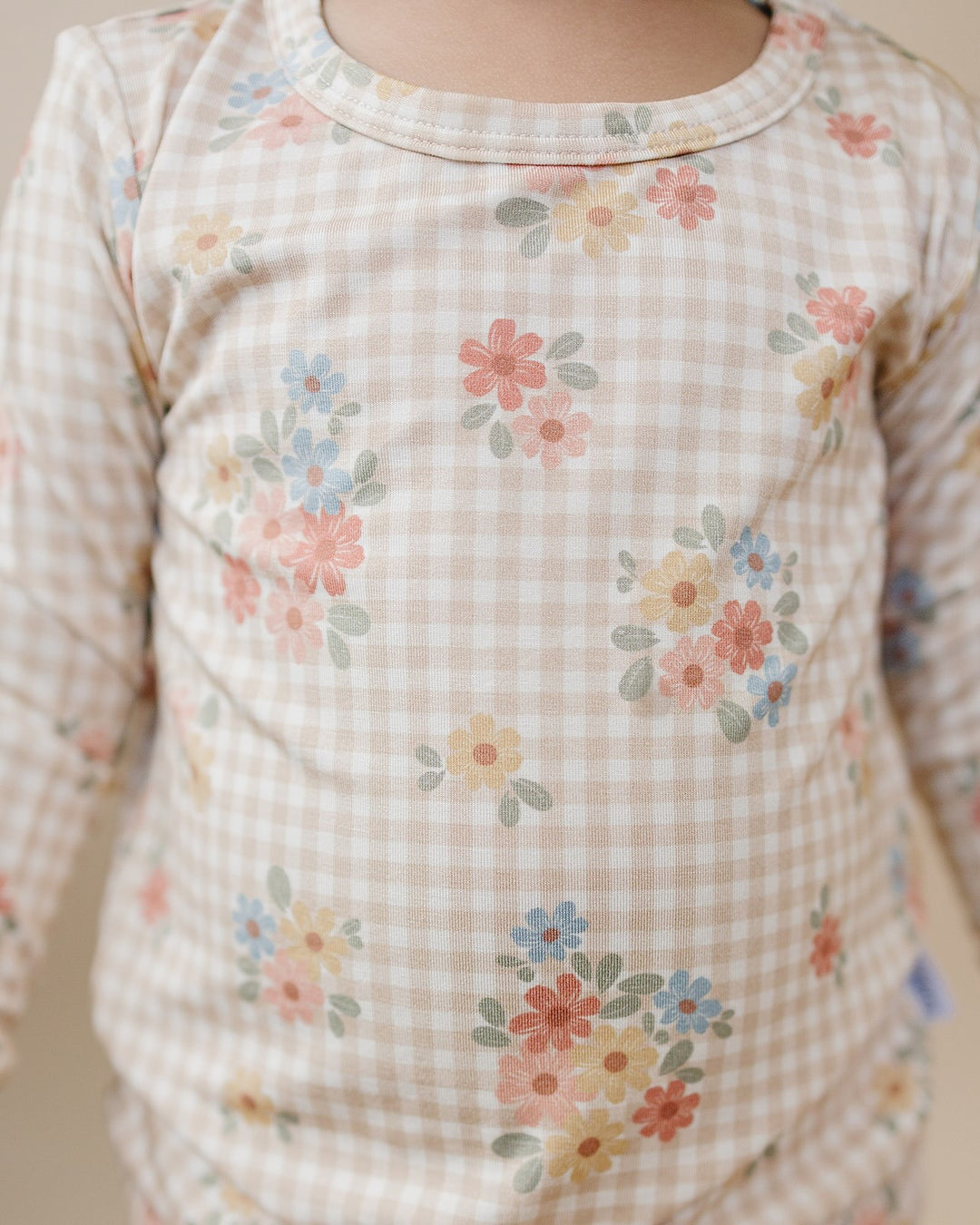 Toddler climbing onto a wooden chair in the Wild Flower bamboo zip romper, showing the back fit.