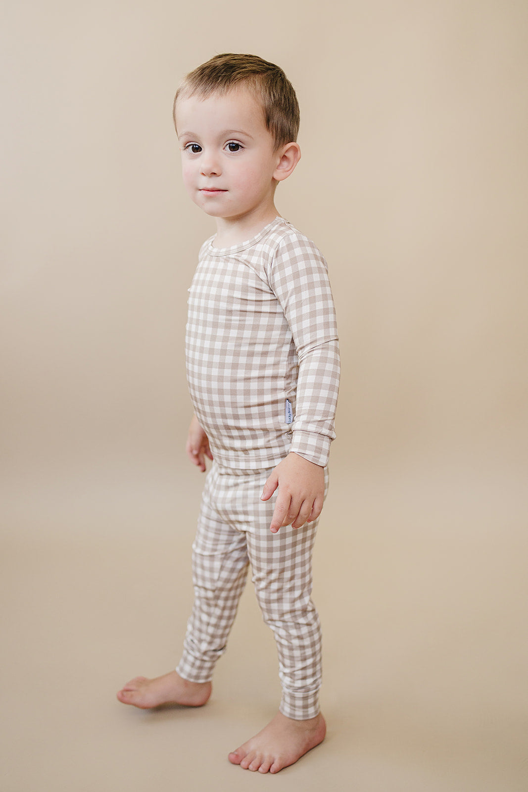 Side view of a toddler wearing the Beige Gingham bamboo two-piece set against a neutral background.