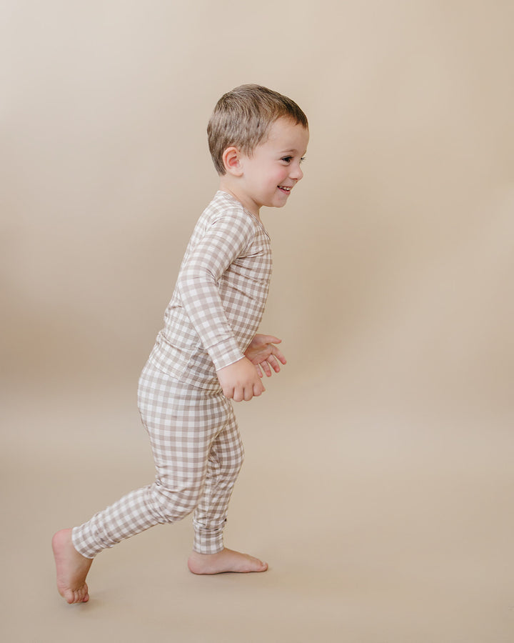 Toddler running in the Beige Gingham bamboo two-piece pajama set, showing its flexible fit.