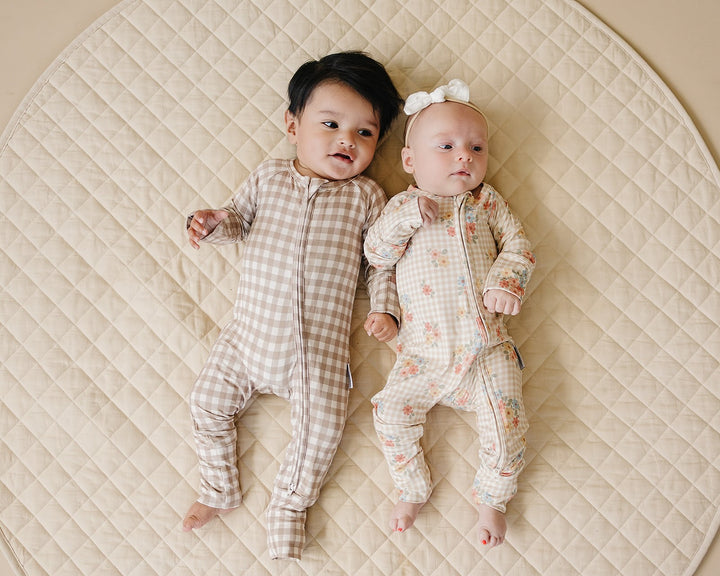 Two babies modeling coordinating Lucky Panda Kids Beige Gingham and floral bamboo zip rompers.