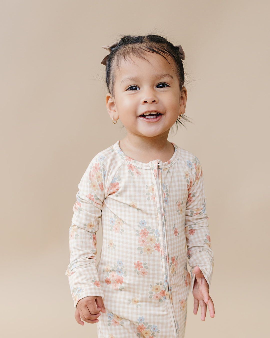 Smiling toddler modeling the Lucky Panda Kids Wild Flower bamboo zip romper in a full-length studio view.