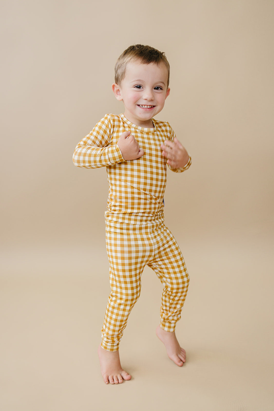 Toddler modeling the Lucky Panda Kids Yellow Gingham bamboo two-piece set in a full-length studio view.
