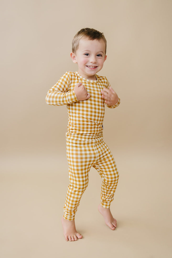 Toddler modeling the Lucky Panda Kids Yellow Gingham bamboo two-piece set in a full-length studio view.
