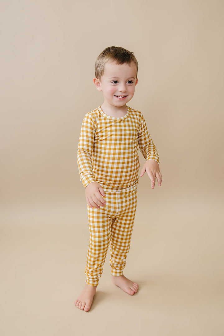 Toddler walking in the Yellow Gingham bamboo two-piece set against a neutral studio background.