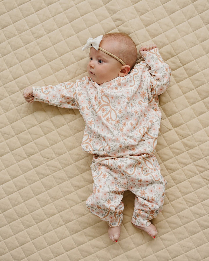 Baby lying comfortably in the Cozy Daisy cotton sweatshirt and matching jogger pants.