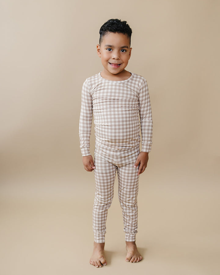 Child modeling the Lucky Panda Kids Beige Gingham bamboo pajama set in a full-length front view.