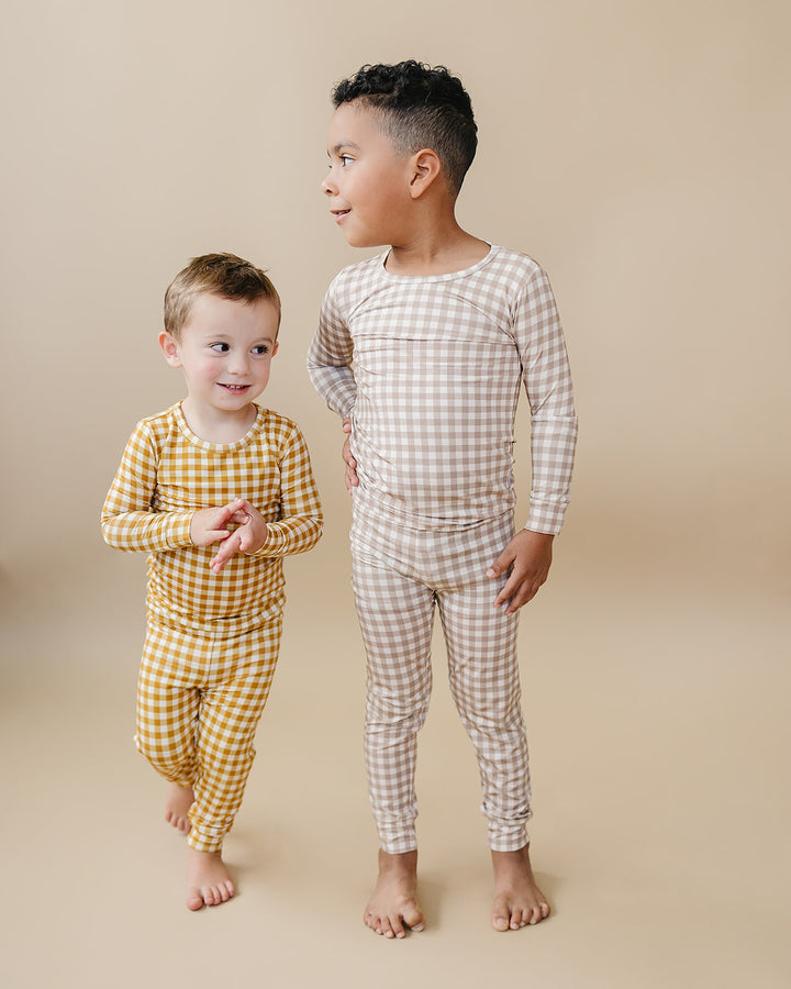 Two children standing together in matching Lucky Panda Kids Beige Gingham bamboo pajama sets.