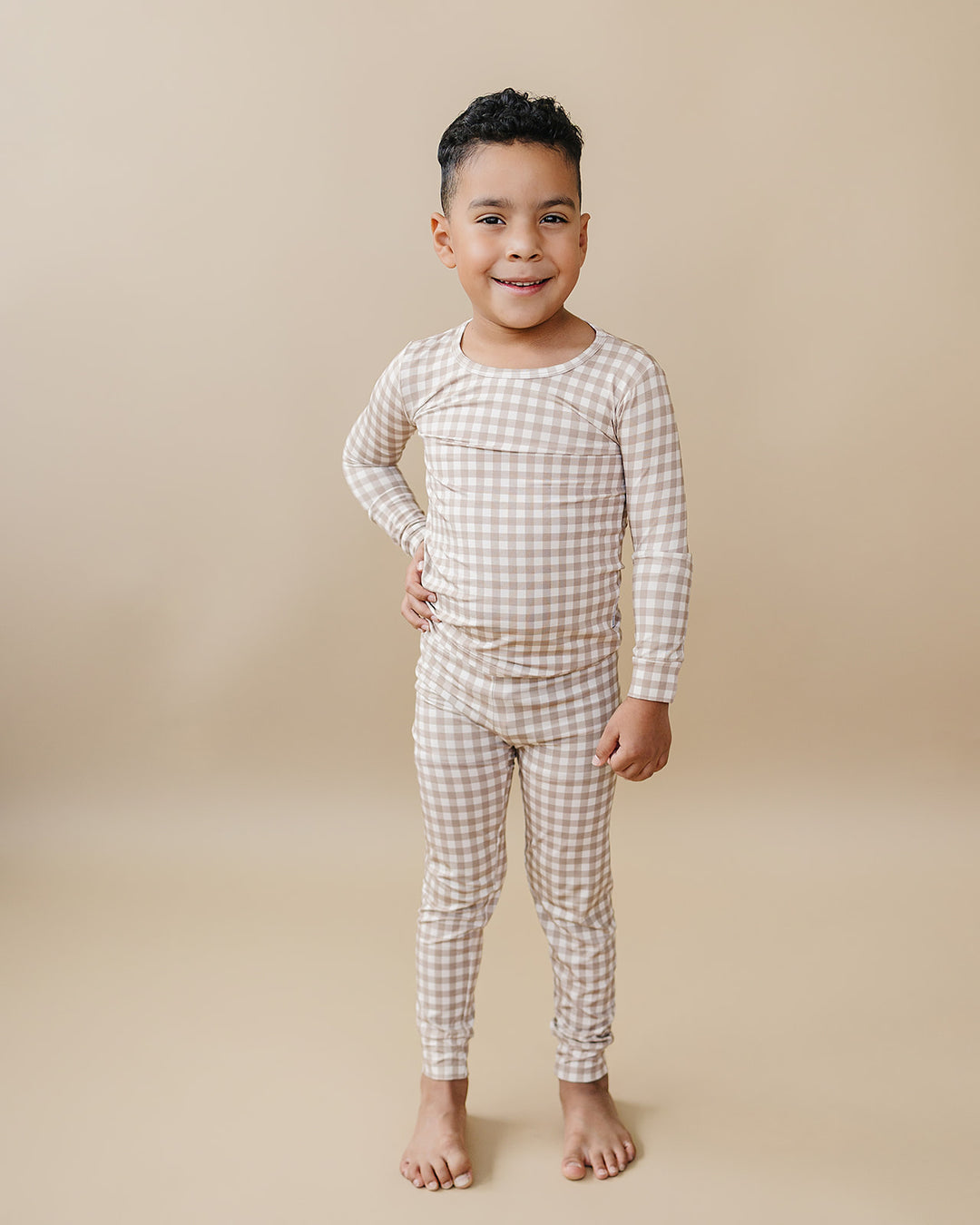 Smiling child posing in the Lucky Panda Kids Beige Gingham bamboo two-piece set.