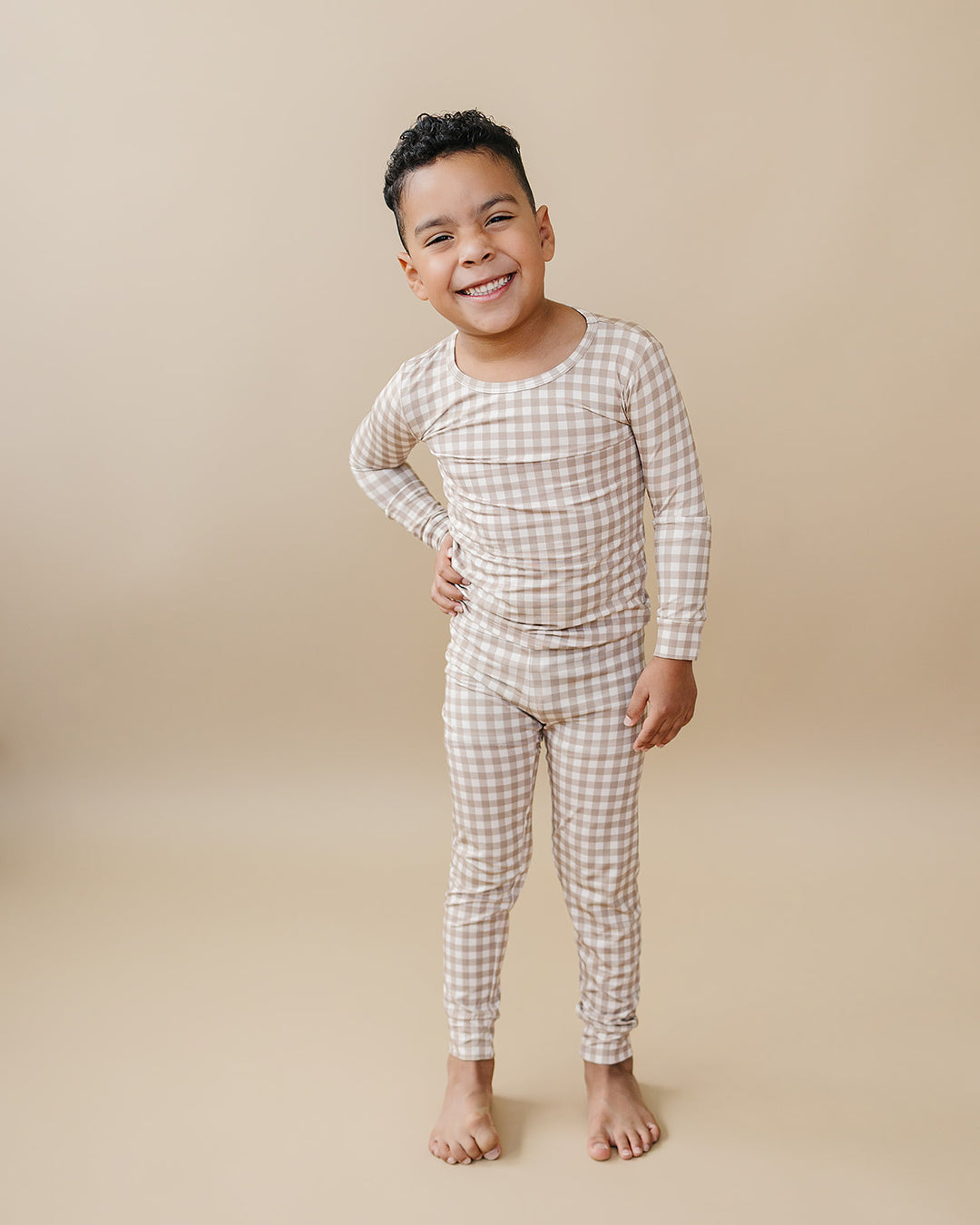 Smiling child modeling the Lucky Panda Kids Beige Gingham bamboo two-piece pajama set.