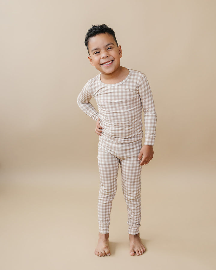 Smiling child modeling the Lucky Panda Kids Beige Gingham bamboo two-piece pajama set.