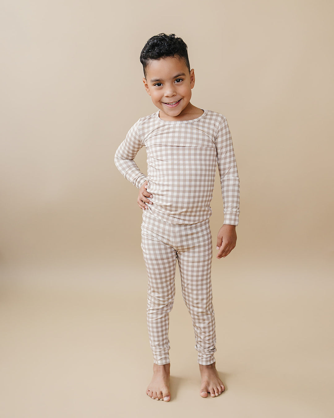 Full-length studio view of a child wearing the Beige Gingham bamboo pajama top and matching pants.