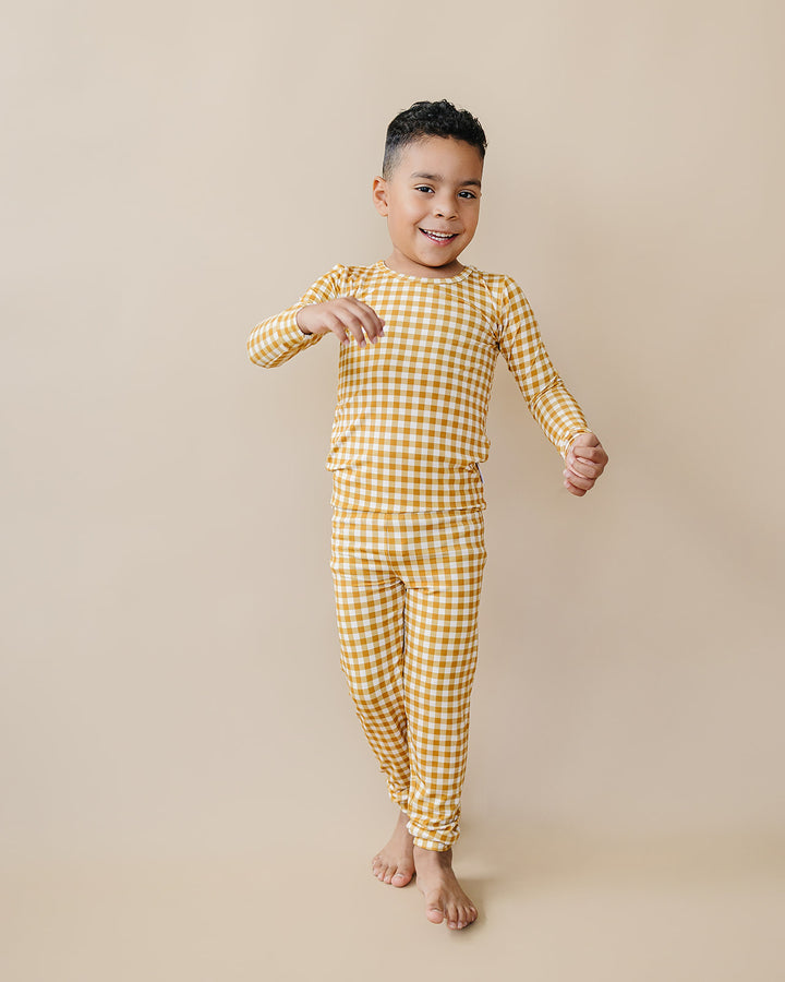 Full-length view of a child walking in the Lucky Panda Kids Yellow Gingham bamboo pajama set.