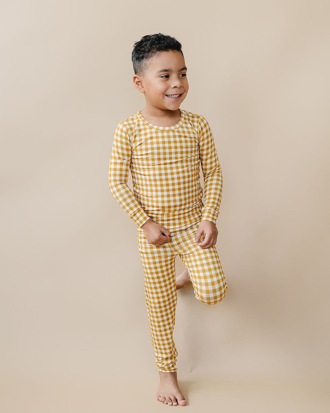 Child walking in the Yellow Gingham bamboo pajama set against a warm neutral background.