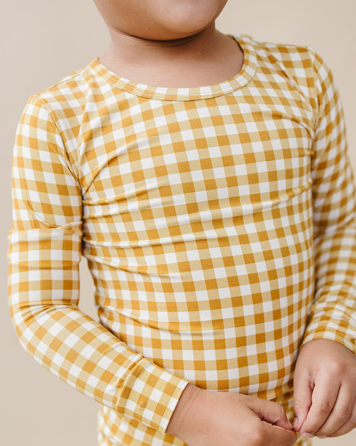 Close-up of a child wearing the Yellow Gingham bamboo two-piece set in a mustard-yellow checkered print.