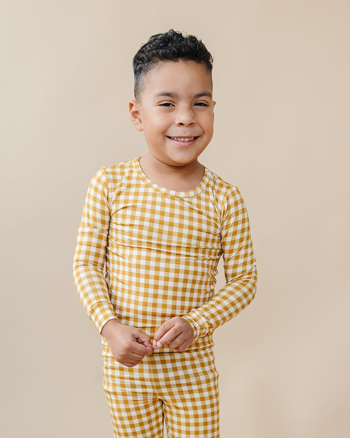 Smiling child modeling the Lucky Panda Kids Yellow Gingham bamboo two-piece pajama set.