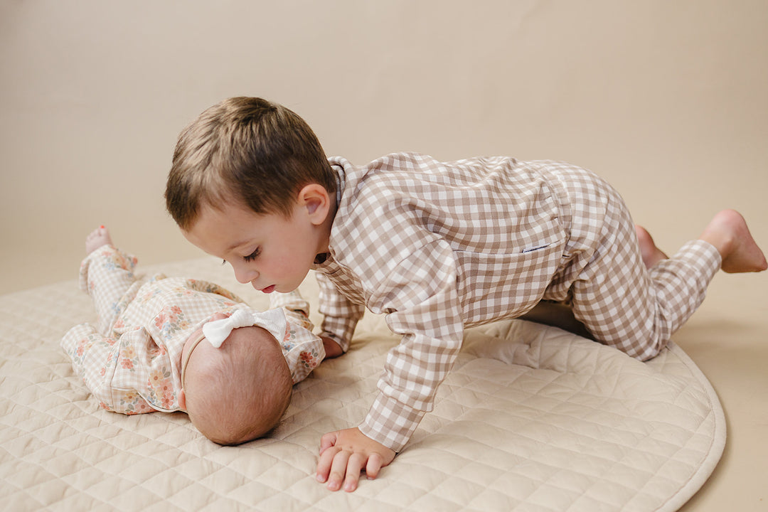 Child playing with a baby while wearing the Lucky Panda Kids Beige Gingham cotton jogger set.