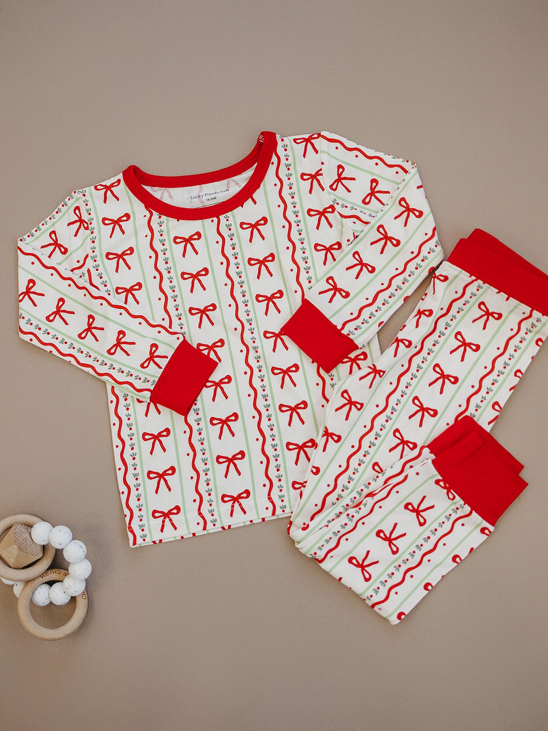 Christmas Bows pajama top and matching pants laid flat, showing rows of red bows and red trim.